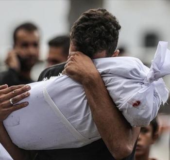 فلسطيني يُشيع طفله الشهيد في غزة.jpeg
