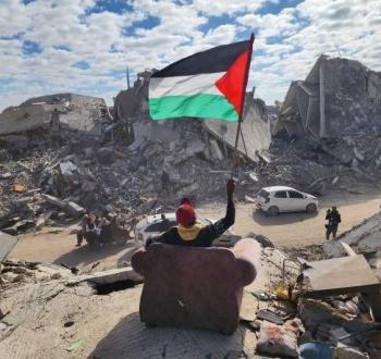 شاب فلسطيني يرفع علم فلسطين وسط الدمار في غزة