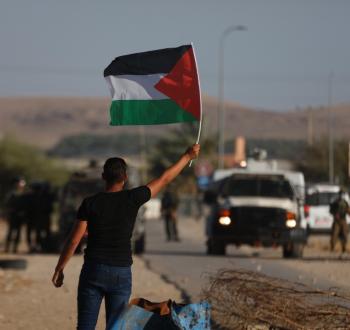 شاب يرفع علم فلسطين خلال مواجهات في الضفة