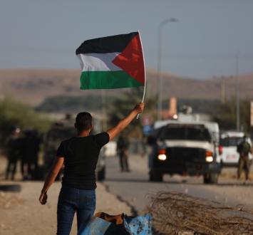 شاب يرفع علم فلسطين خلال مواجهات في الضفة.jpg