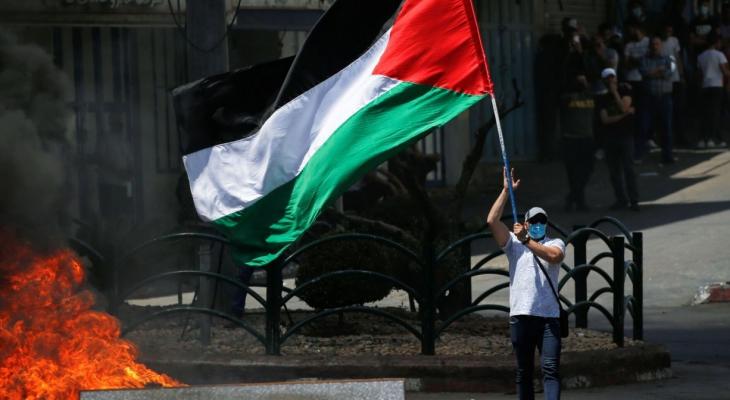 شاب يرفع علم فلسطين خلال مواجهات مع الاحتلال بالضفة