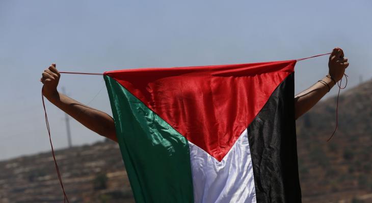 شاب فلسطيني يرفع علم فلسطين خلال المواجهات.jpg