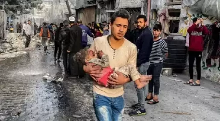 فلسطيني يحمل طفلة شهيدة بقصف إسرائيلي.webp