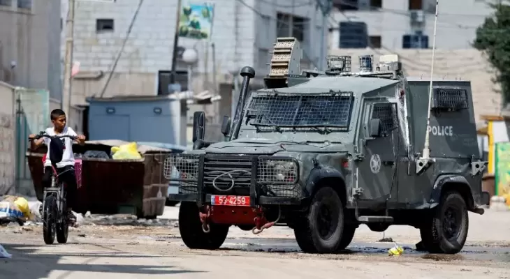 طفل فلسطيني يقطع الطريق من أمام مركبة عسكرية إسرائيلية.webp