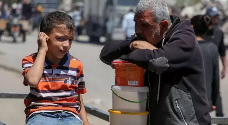 فلسطيني وطفله خلال انتظار مساعدات في غزة.webp