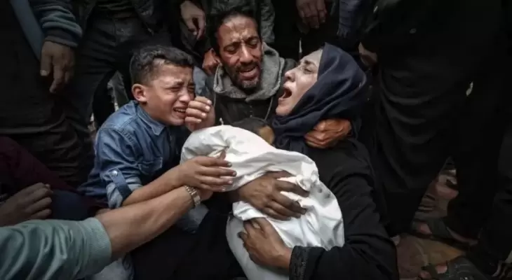 فلسطينية تحتضن طفلها للمرة الأخيرة بعد استشهاده بمجزرة إسرائيلية في غزة.webp