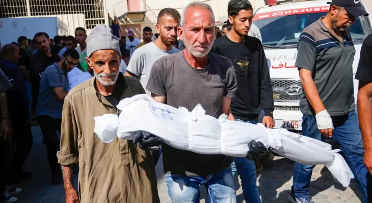 فلسطيني يحمل طفله بعد استشهاده في مجزرة بغزة.webp