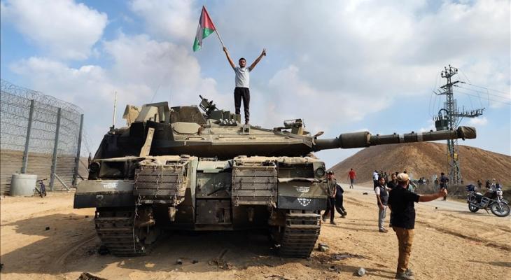 فلسطيني يرفع علامة النصر وعلم فلسطين فوق ميركافاة إسرائيلية.jpeg