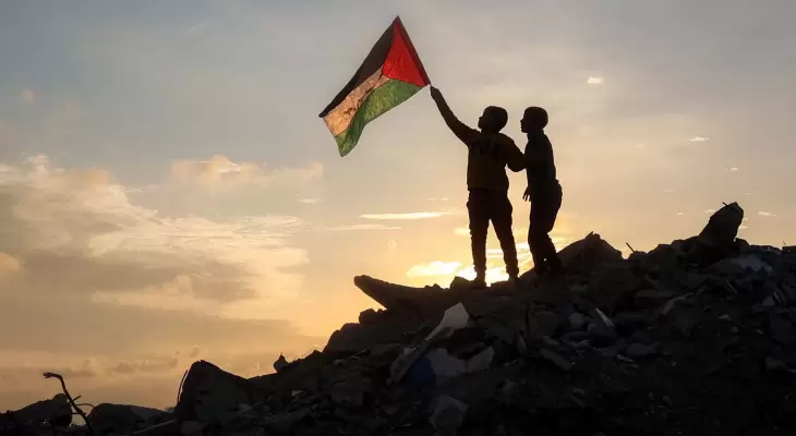 فلسطينيان يرفعان علم فلسطين بغزة.webp