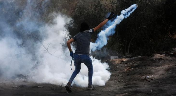 شاب فلسطيني يعيد قنبلة غاز باتجاه قوات الاحتلال.jpg