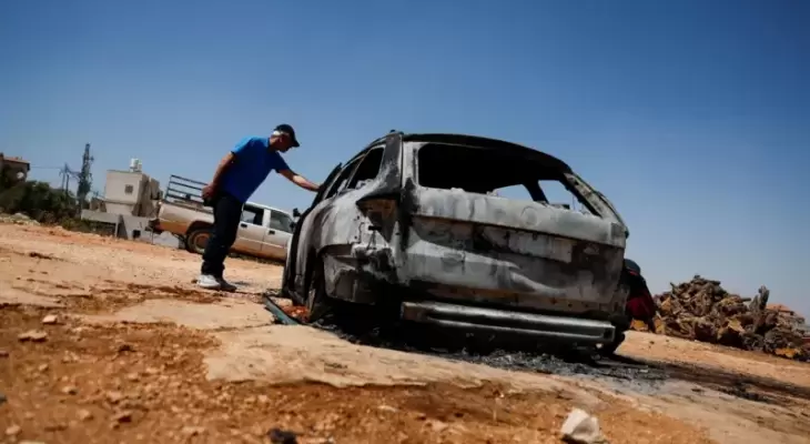 فلسطيني يتفقد سيارة محترقة بعد هجوم شنه مستوطنون على قرية كفر مالك.webp