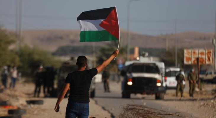 شاب يرفع علم فلسطين خلال مواجهات في الضفة.jpg