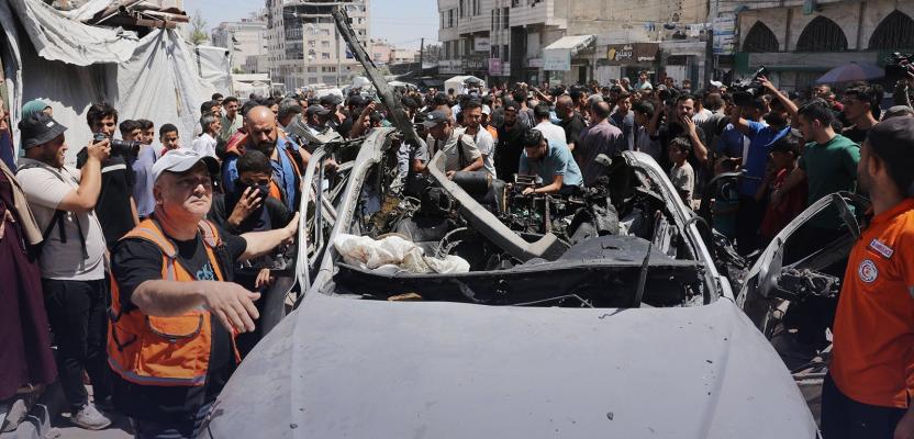 فلسطينيون يتجمعون حول مركبة مدمرة في مدينة غزة بعد استهدافها بغارة إسرائيلية