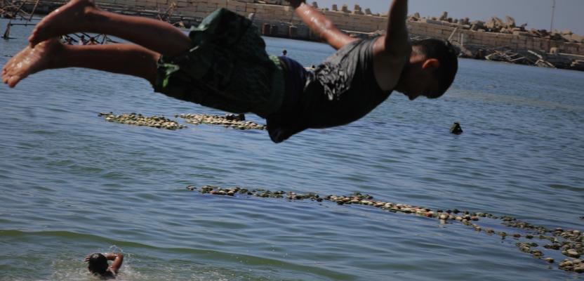 أطفال يقضون أوقاتاً على شاطئ بحر مدينة غزة خلال يوم حار