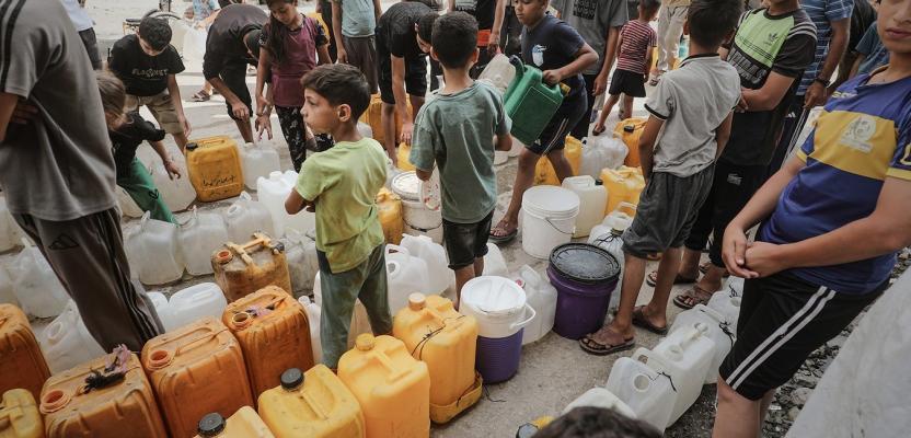 طوابير طويلة من الفلسطينيين أمام عربة مياه للحصول على كميات شحيحية من مياه الشرب في مخيم البريج