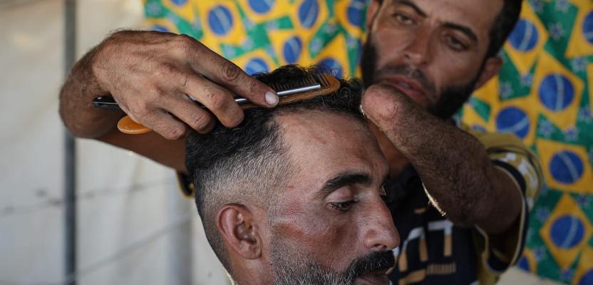 تحدٍ للظروف والإعاقة.. الحلاق جهاد المبحوح يواصل مهنته من داخل خيمة نزوح في مخيم النصيرات