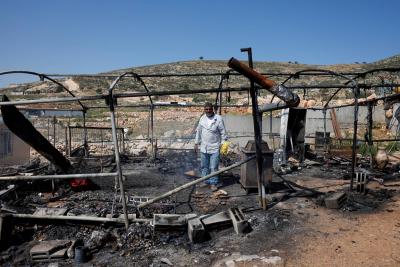 فلسطيني يتفقد أضراراً بممتلكاته إثر هجوم المستوطنين على قرية المغير.jpeg