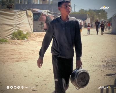 مواطنون يتجمعون للحصول على الطعام من تكية خيرية في دير البلح وسط قطاع غزة.11.jpg