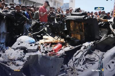 فلسطينيون وعناصر من الدفاع المدني يتجمعون حول مركبة مدمرة في مدينة غزة بعد استهدافها بغارة إسرائيلية2.jpg